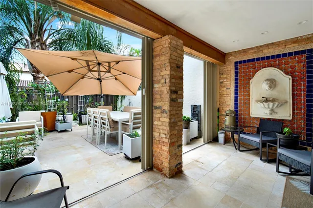 a view of a patio with a table and chairs under an umbrella with a fire pit