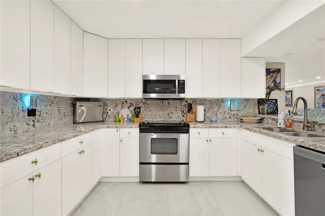 a kitchen with granite countertop white cabinets and stainless steel appliances