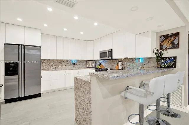 a kitchen with stainless steel appliances granite countertop a refrigerator and a stove top oven