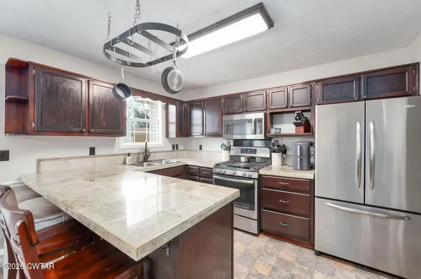 a kitchen with granite countertop a center island stainless steel appliances cabinets and a window