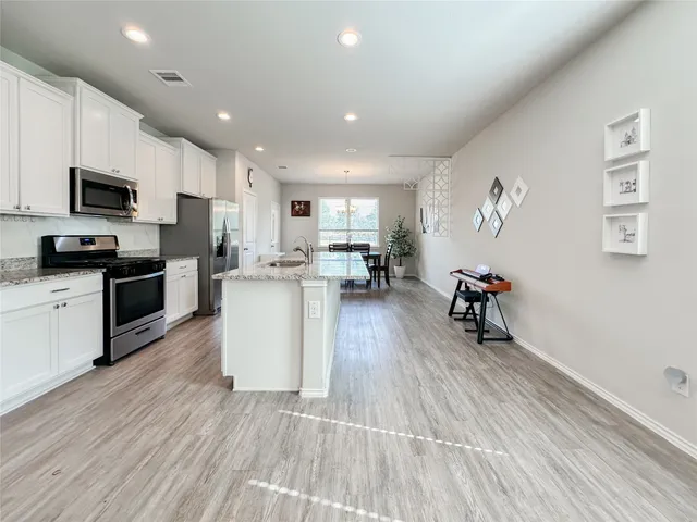 a living room with stainless steel appliances furniture and a wooden floor