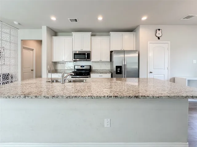a kitchen with granite countertop a sink stainless steel appliances and cabinets