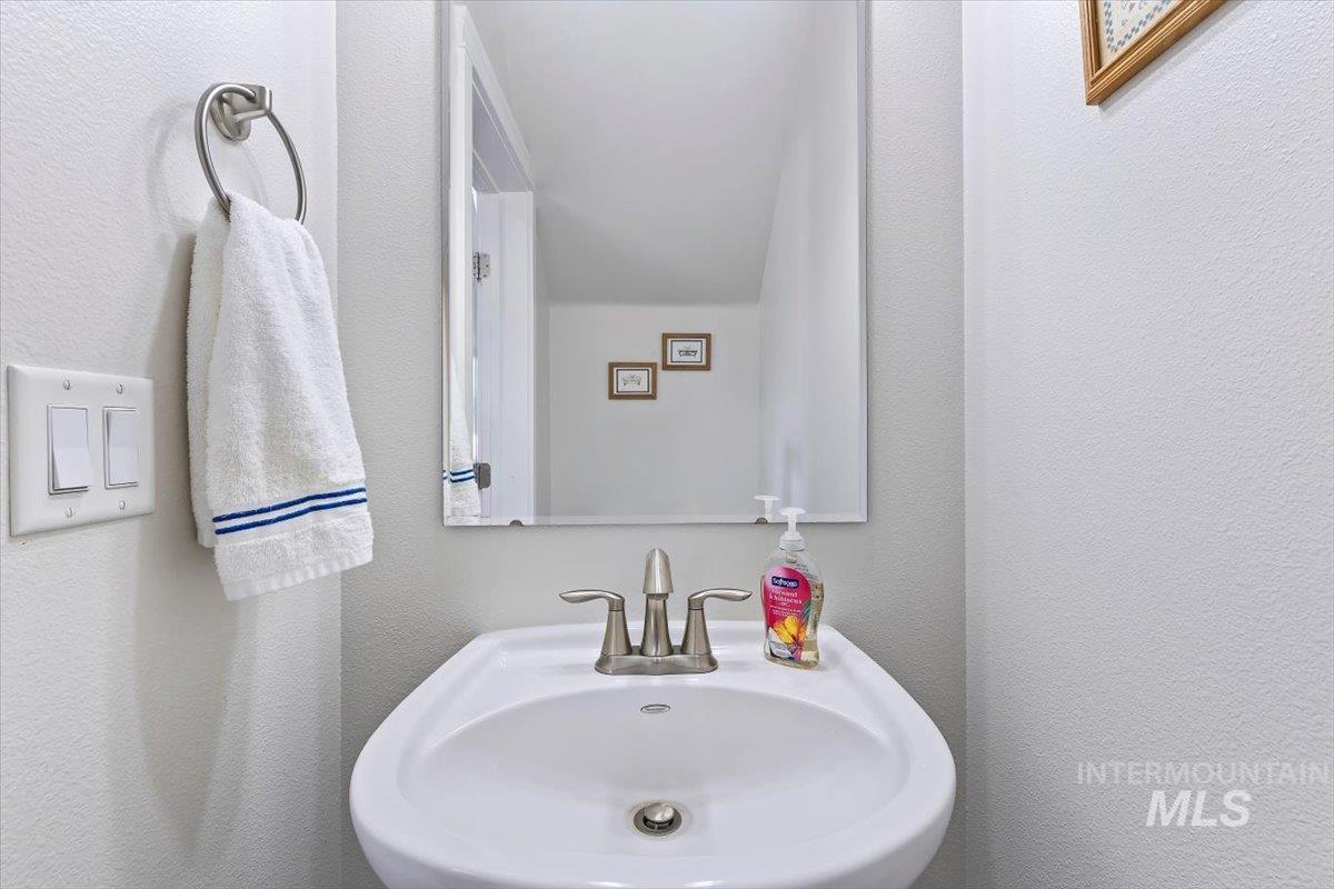 4390 North Five Mile Road Boise, ID 83704 - Photo 11 of 23 Pedestal sink with a brushed nickel faucet and a wall-mounted mirror