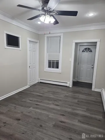 a view of an empty room with wooden floor and a ceiling fan