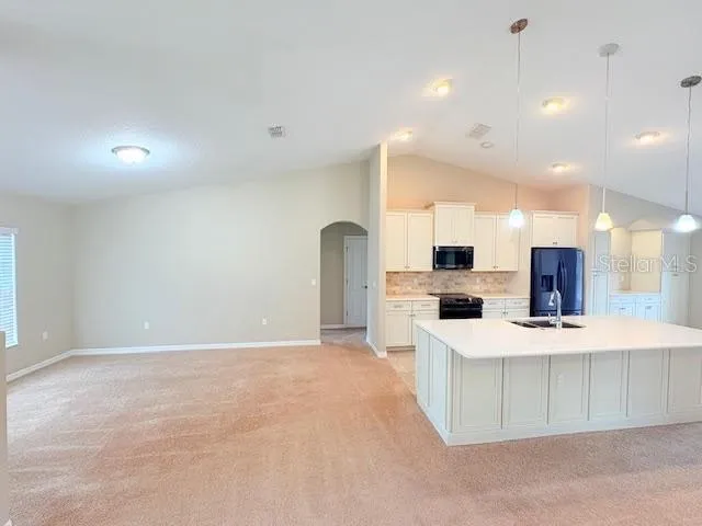 a view of a kitchen with kitchen island a sink stainless steel appliances and cabinets