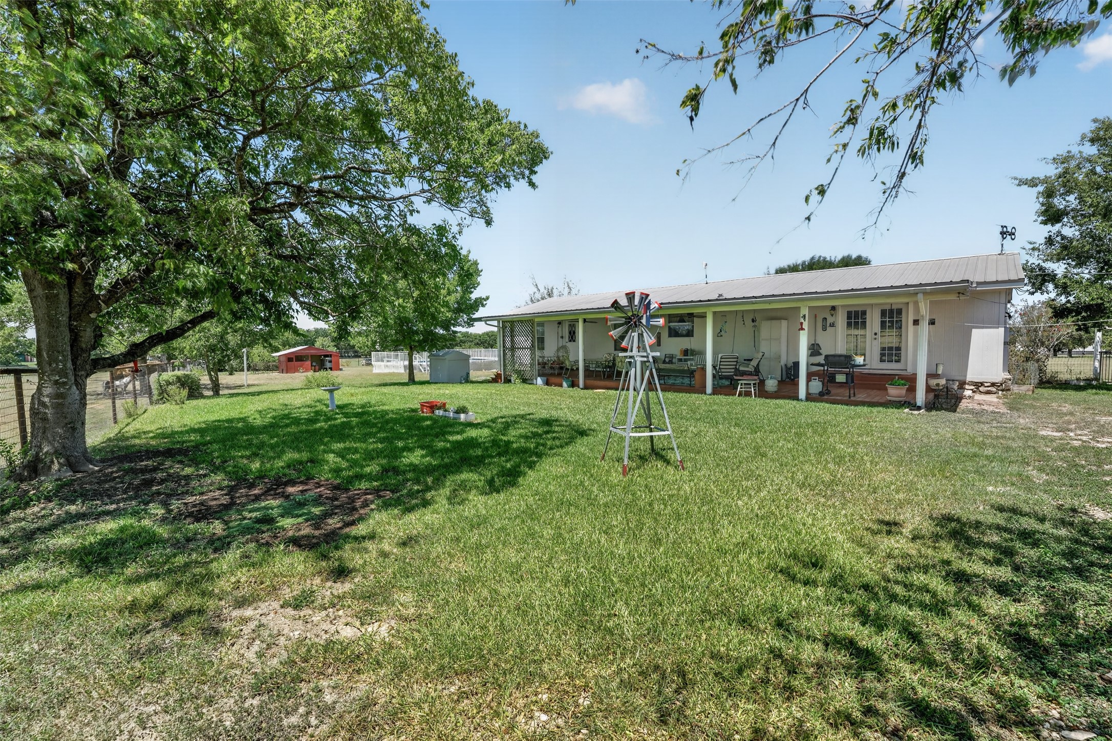 317 Rae Lane Jarrell, TX 76537 - Photo 14 of 40 A spacious backyard with mature trees provides ample shade and a charming windmill accent, perfect for outdoor living.