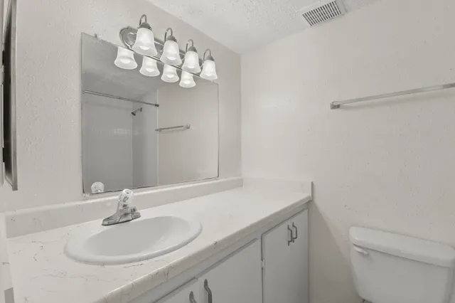 a bathroom with a sink vanity granite and toilet