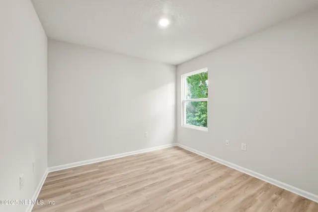 an empty room with wooden floor and window