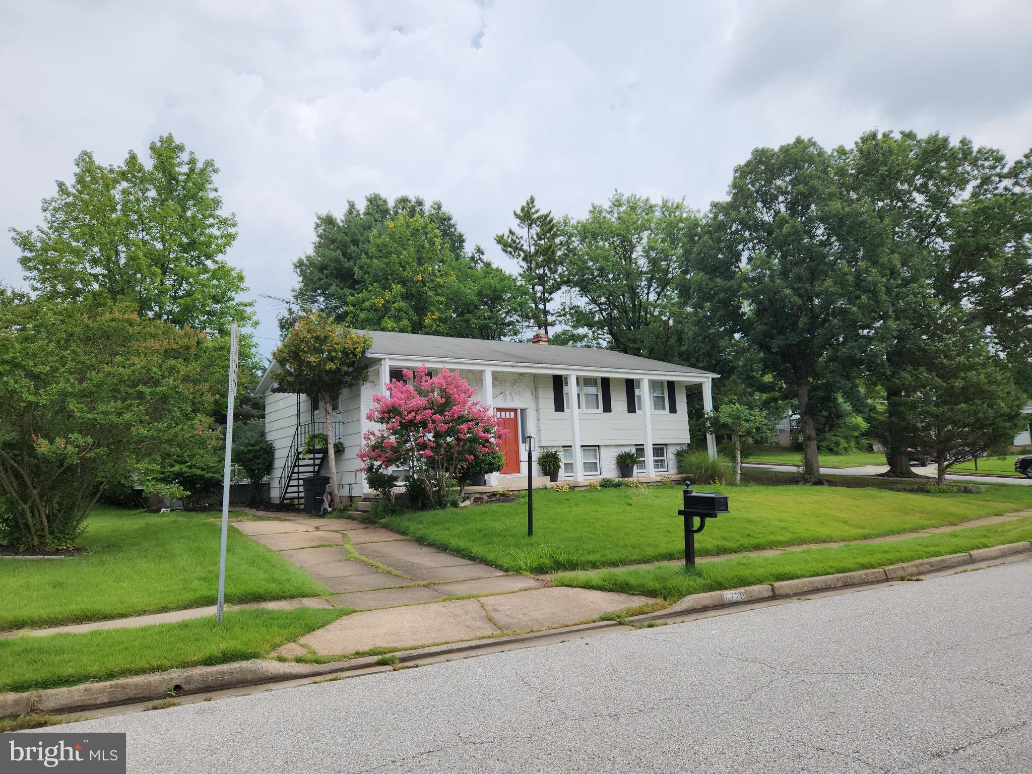 6720 Garvey Road Baltimore, MD 21237 - Photo 5 of 13 a view of a white house with a big yard and large trees