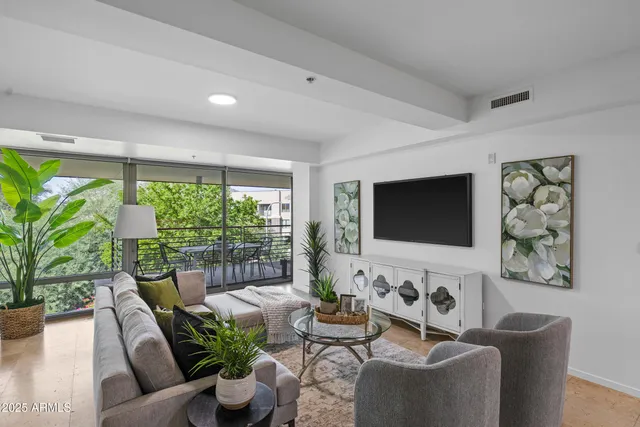 a living room with furniture potted plant and a large window