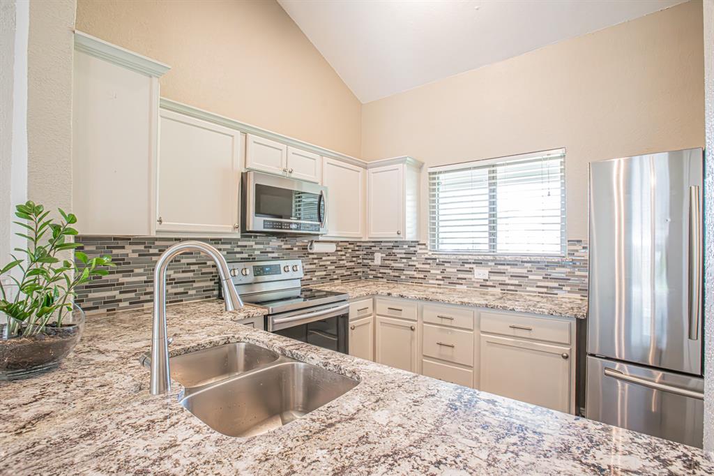 818 Little Creek Drive Euless, TX 76039 - Photo 1 of 1 Kitchen featuring a sink, stainless steel appliances, lofted ceiling, and decorative backsplash