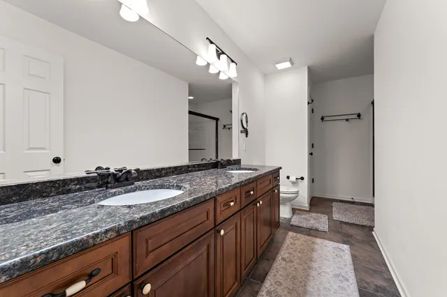 a spacious bathroom with a granite countertop sink a mirror and a shower