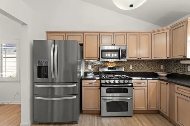 a kitchen with cabinets stainless steel appliances and wooden floor