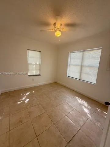 en empty room with windows and chandelier fan