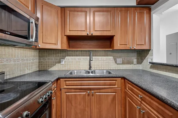 a kitchen with granite countertop a sink stove and cabinets