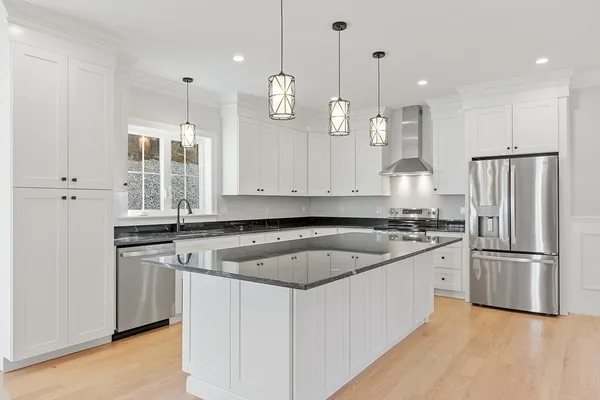 a kitchen with stainless steel appliances granite countertop a sink a stove a refrigerator and island with wooden floor