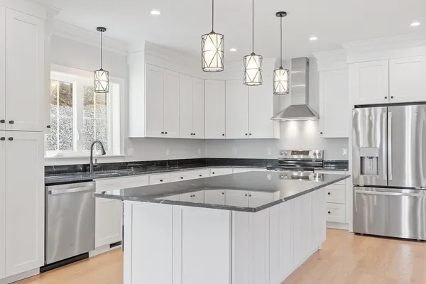 a kitchen with stainless steel appliances granite countertop a sink a stove a refrigerator and island with wooden floor