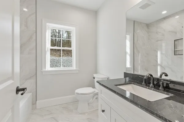 a bathroom with a granite countertop sink a toilet and a mirror