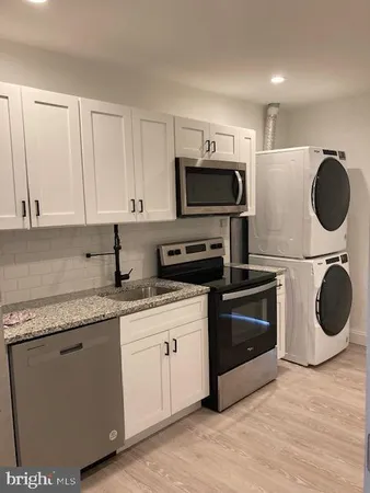 a kitchen with stainless steel appliances granite countertop a sink a stove and microwave with wooden floor