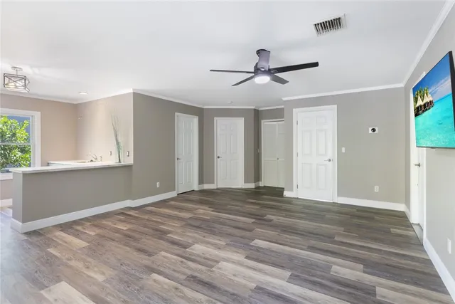 a view of empty room with wooden floor and fan