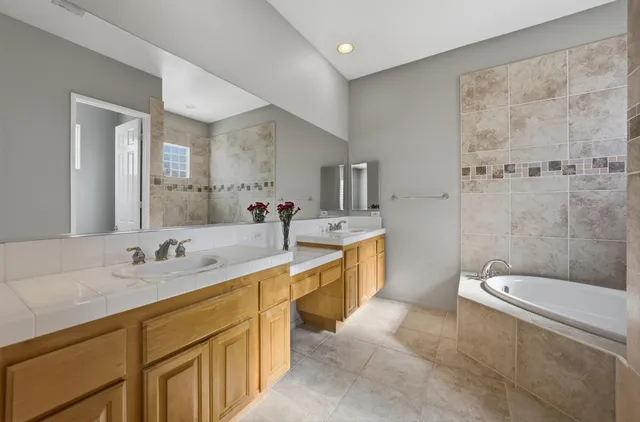a spacious bathroom with a double vanity sink toilet mirror and bathtub