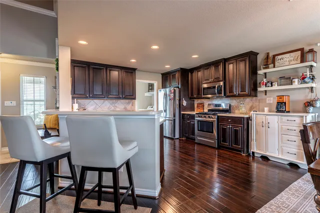 a kitchen with stainless steel appliances granite countertop a stove a sink a refrigerator and a refrigerator with wooden floor