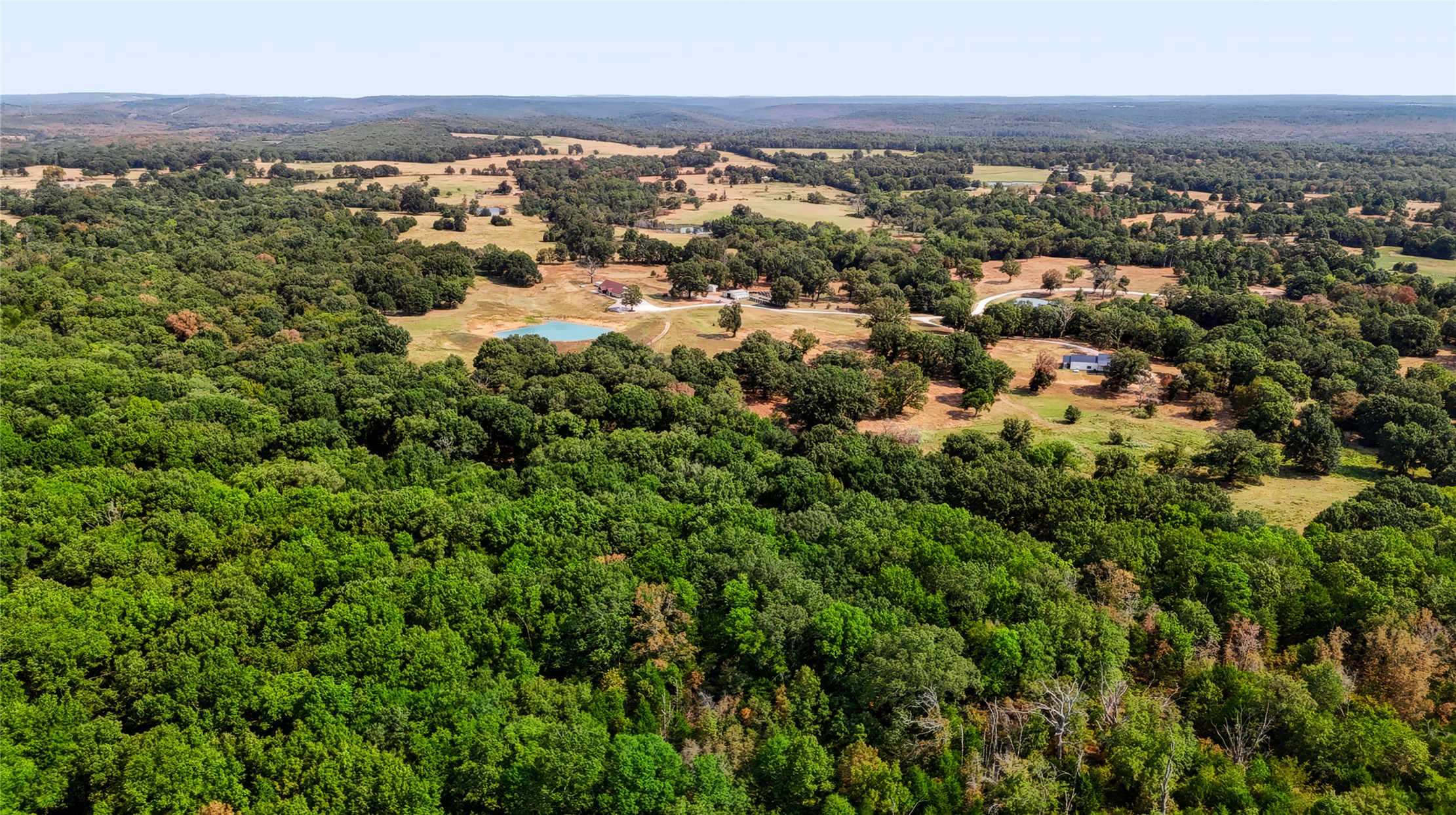 3607 South Half Bank Road Atoka, OK 74525 - Photo 76 of 82 Expansive wooded landscape with scattered clearings, featuring a prominent pond and distant structures