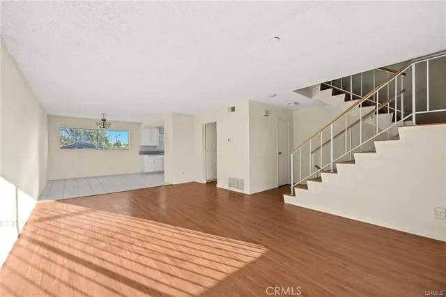 a view of an empty room with wooden floor and stairs