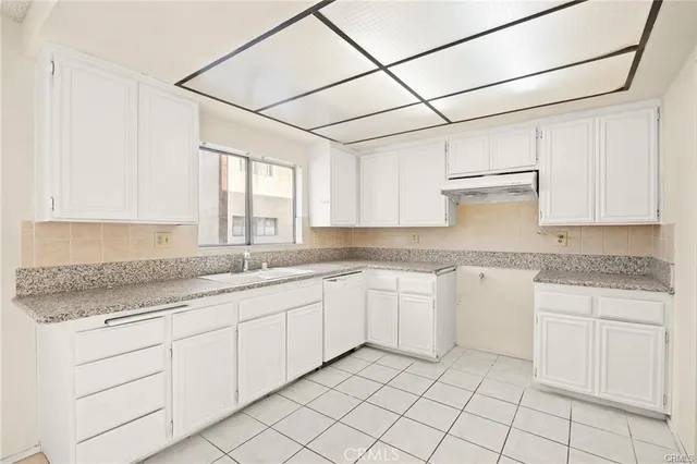 a kitchen with granite countertop white cabinets white appliances sink and dishwasher