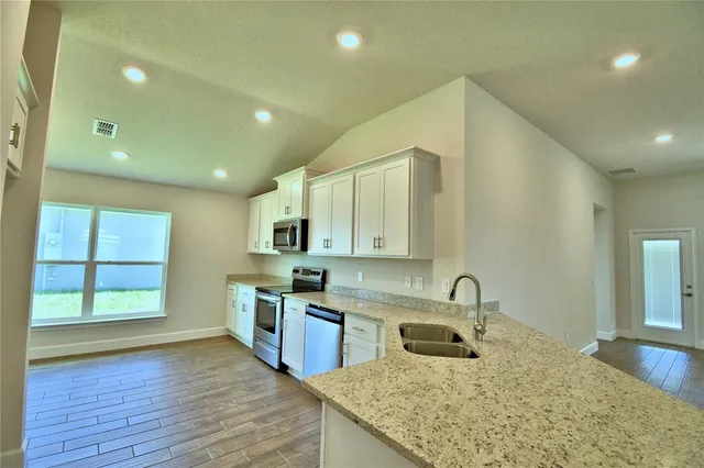 a kitchen with kitchen island granite countertop wooden cabinets stainless steel appliances and a window