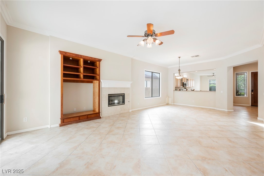 17 Caprington Road Henderson, NV 89052 - Photo 12 of 34 Unfurnished living room with ornamental molding, a tile fireplace, a ceiling fan, and light tile patterned floors