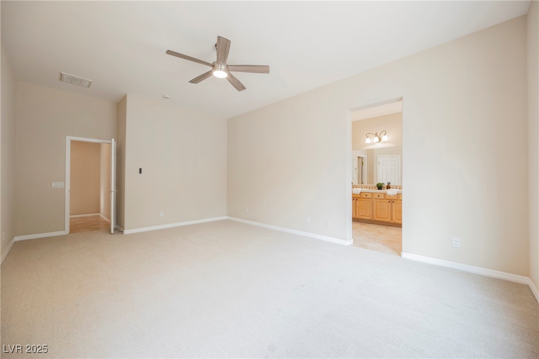 17 Caprington Road Henderson, NV 89052 - Photo 14 of 34 Unfurnished bedroom featuring light colored carpet, connected bathroom, and ceiling fan