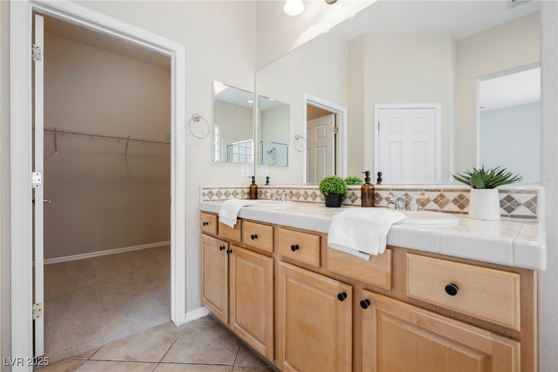17 Caprington Road Henderson, NV 89052 - Photo 15 of 34 Bathroom with tile patterned flooring, double vanity, tasteful backsplash, and a walk in closet