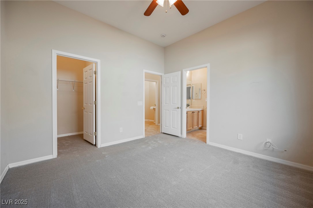 17 Caprington Road Henderson, NV 89052 - Photo 18 of 34 Unfurnished bedroom with a spacious closet, light colored carpet, connected bathroom, and ceiling fan
