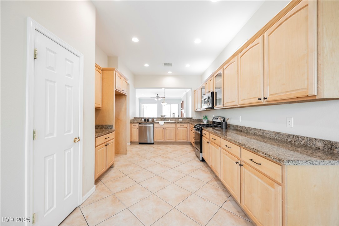 17 Caprington Road Henderson, NV 89052 - Photo 10 of 34 Kitchen with light brown cabinetry, appliances with stainless steel finishes, light tile patterned flooring, recessed lighting, and glass insert cabinets