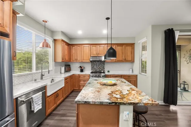 a kitchen with stainless steel appliances granite countertop wooden cabinets a refrigerator and a stove