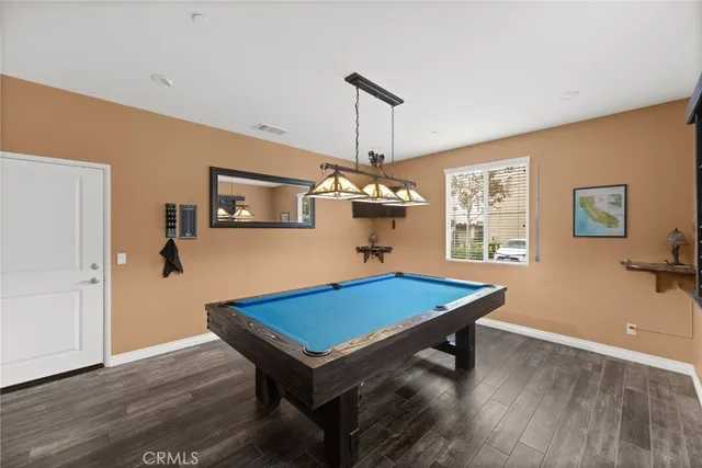 a room with wooden floor pool table and windows