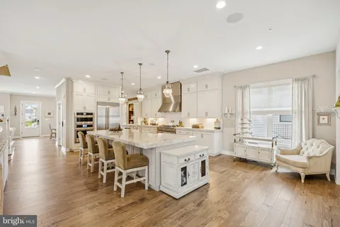 a kitchen with stainless steel appliances a dining table chairs stove and white cabinets