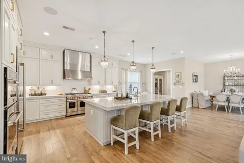a large kitchen with cabinets chairs and wooden floor