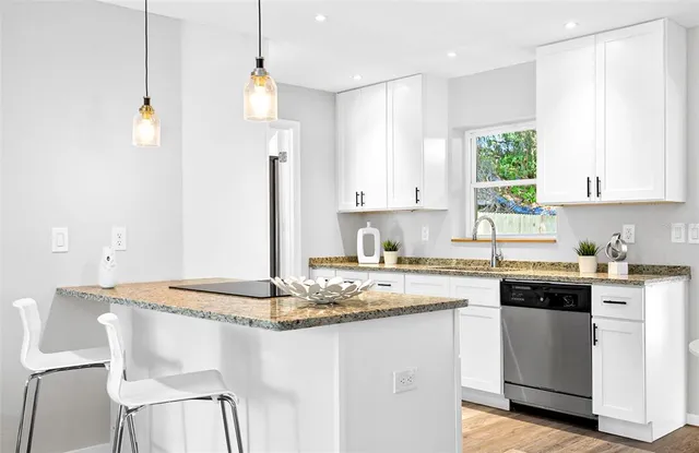 a kitchen with kitchen island granite countertop a sink cabinets and window