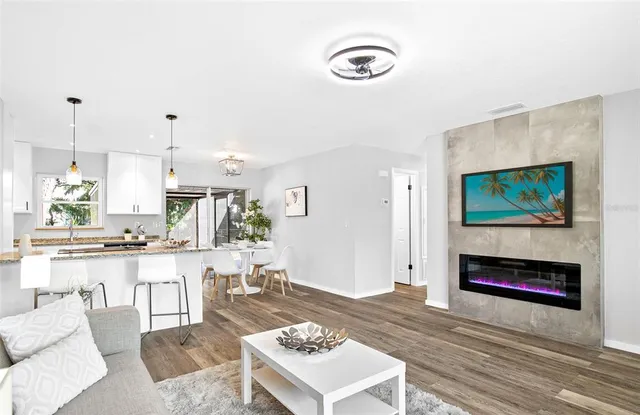 a living room with stainless steel appliances furniture a fireplace and a flat screen tv