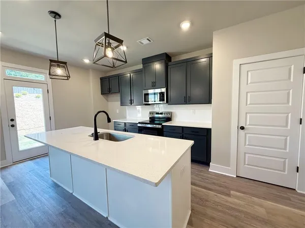 a kitchen with a refrigerator a sink and dishwasher with wooden floor