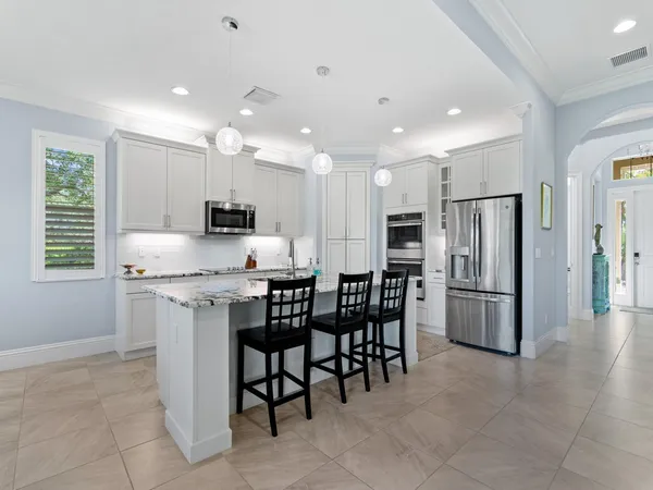 a kitchen with stainless steel appliances granite countertop a table chairs sink refrigerator and microwave