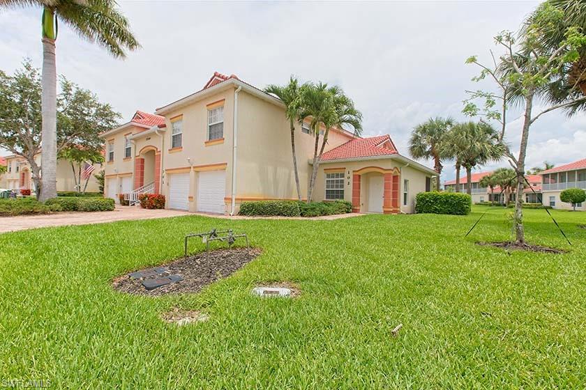 25064 Peacock Lane, Unit 102 Naples, FL 34114 - Photo 2 of 21 a front view of a house with a yard and trees