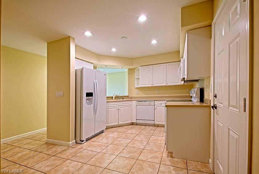 25064 Peacock Lane, Unit 102 Naples, FL 34114 - Photo 9 of 21 a kitchen with a refrigerator and a stove top oven