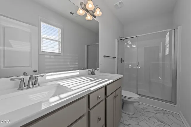 a bathroom with a sink a toilet a mirror and shower