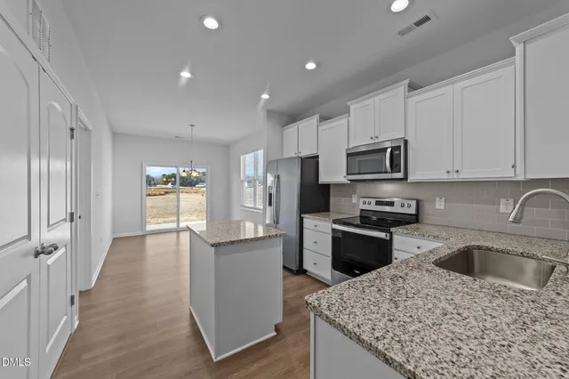 a kitchen with a sink dishwasher a stove top oven a refrigerator with grey cabinets and wooden floor