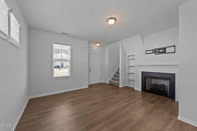 an empty room with windows and fireplace