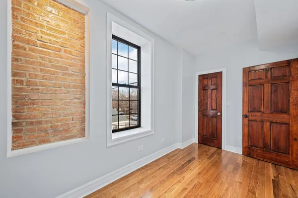 a view of an empty room with window and wooden floor