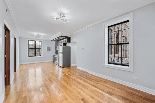 a view of an empty room with window and wooden floor